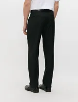 Ambo semi slim de color negro, compuesto por un saco estructurado de dos botones con solapa de muesca tradicional y un pantalón de corte contemporáneo.