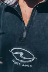 Buzo de algodón con efecto lavado, cuello alto con medio cierre frontal, mangas largas y corte holgado. Presenta un estampado gráfico en el pecho con la inscripción 'Glassy Waves'.