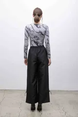 Top negro de mangas largas con frunces en el hombro izquierdo.