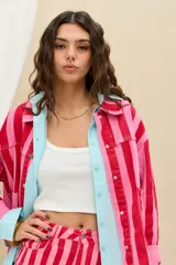 Campera de denim con diseño de rayas verticales en tonos rojo y rosado, cuello clásico, cierre frontal con botones metálicos y bolsillos appliqued en el frente.