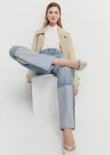Pantalón de jean de corte recto y tiro medio, confeccionado en algodón. Presenta un diseño distintivo con el bajo vuelto en un tono de denim más claro y una costura lateral vertical en contraste.