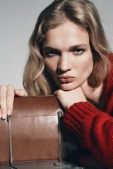 Bolso de hombro de piel marrón oscuro, formato rígido y rectangular, con detalle de pespuntes que crean un patrón de cuadrados. Posee triple compartimento y doble asa de hombro en cadena metálica dorada.