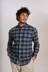 Camisa de manga larga confeccionada en tejido de franela con estampado de cuadros en tonos azul marino y verde. Presenta cuello abotonado, cierre frontal con botones y un bolsillo en el pecho con el logo bordado de la marca.