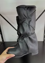 Botas bucaneras de cuero vegano en color negro, con diseño de caña holgada y efecto arrugado. Presentan punta redondeada y suela plana.