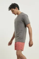 Remera gris con bolsillo ojal en el pecho, de manga corta y cuello redondo.