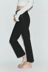 Jeans de tiro alto con diseño cropped flare, confeccionados en denim azul con acabado desgastado. Presentan cinco bolsillos, cierre frontal con cremallera y botón metálico, y bajo con terminación sin costuras.