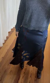 Falda midi de tiro medio confeccionada en tela sedosa color azul marino con estampado floral y aberturas frontales.