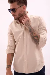 Camisa de manga larga color beige, con cuello clásico y botones frontales.