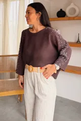Sweater gris melange con detalles de perlas y strass aplicados en las mangas, de corte holgado y mangas largas.