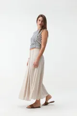 Falda larga beige de corte evasé, con diseño fluido y detalles de costuras verticales en la parte delantera.