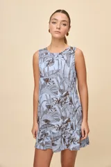 Vestido corto sin mangas de color celeste con estampado botánico en tonos marrones, de silueta amplia, escote redondo y volado en el ruedo.