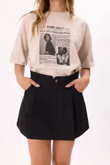 Remera de algodón color beige con corte oversize y estampa frontal estilo editorial con texto y fotografías en blanco y negro.