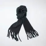 Bufanda de tejido suave en color negro, con diseño de flecos en los extremos.