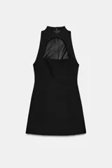 Vestido mini negro sin mangas, con cuello mao, abertura frontal tipo lágrima y forro interior a tono. Cierre en la espalda con cremallera oculta.