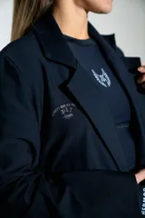 Blazer de lycra color negro, de corte oversize y diseño estructurado con solapas clásicas. Presenta detalles bordados sutiles en la solapa y en el puño de la manga.
