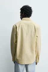 Camisa de corte regular fit de tejido de algodón, con diseño de rayas verticales amarillas y azules. Cuenta con cuello abotonado, manga larga con puños abotonados, un bolsillo aplicado en el pecho y cierre frontal con botones.