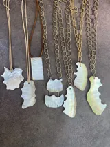 Collar dorado con cadena gruesa y dije doble de nácar con forma irregular.