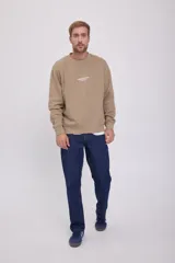 Buzo de cuello redondo y manga larga, corte relajado en color beige. Presenta el logotipo "Originals Studio" estampado en pequeño en el pecho.