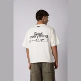 Remera boxy de calce corto y ancho, color verde oliva, con cuello redondo, mangas cortas y estampa frontal minimalista con texto y logo.