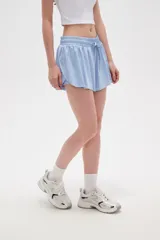 Short de poliéster color celeste, de calce holgado y tiro alto, con cintura elástica ajustable mediante cordón y bolsillos laterales.