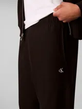 Jogger de felpa Calvin Klein color negro, con cintura elástica, bolsillos laterales y puños acanalados en los tobillos. Presenta el monograma de la marca bordado discretamente en la pierna.