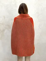 Poncho de lana gris con cuello alto y diseño de rayas verticales en dos tonos de gris.
