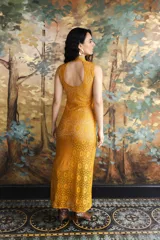Vestido largo de encaje azul con diseño geométrico y detalles en dorado. Cuenta con cuello alto, abertura frontal en el escote y botones dorados decorativos a un costado.