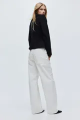 Top de manga larga en punto de algodón con cuello redondo, hombros caídos y detalle de frunces laterales que generan un bajo acampanado.