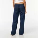 Pantalón de jean con corte baggy y pierna ancha, de tiro medio y color azul oscuro, con cierre frontal y bolsillos laterales.