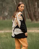 Cárdigan negro de lana con apliques de hojas en tonos beige, naranja y marrón.