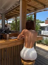 Vestido largo blanco de tejido texturizado, con escote halter anudado y aberturas laterales pronunciadas en la cadera.