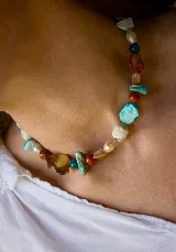 Collar corto de piedras naturales y cuentas multicolor en tonos turquesa, rojo, marrón y beige, con cierre de cadena ajustable.