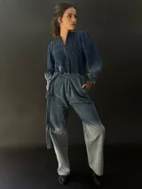 Mono largo de jean azul con lavado artesanal, escote en V regulable con cierre invisible, mangas largas abullonadas y lazo en la cintura.