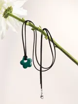 Collar de tiento de cuero con dije de porcelana en forma de flor esmaltada en rojo.