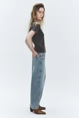 Jeans de tiro medio con corte cropped y diseño de costuras torcidas. Presenta trabillas en la cintura, cinco bolsillos clásicos y cierre frontal con cremallera y botón metálico.