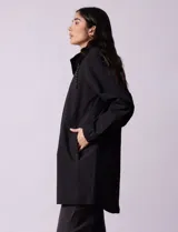 Gabardina impermeable color beige, marca Weatherproof, con cierre central, bolsillos delanteros con botones a presión, capucha desmontable y forro interno.