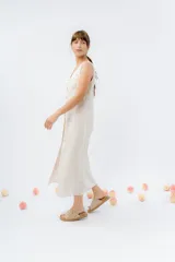 Vestido largo de lino con escote en V, diseño recto y fluido, con cierre frontal abotonado mediante botones de madera.