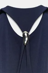 Vestido midi de tejido elástico color azul marino, con cuello halter, aberturas en la espalda y detalle de aplique metálico.