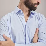 Camisa de vestir negra de manga larga, confeccionada en tejido técnico elástico y libre de arrugas, con cuello clásico y cierre frontal de botones.