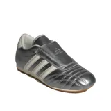 Championes Adidas modelo Taekwondo, color plateado metalizado con las tres tiras características en blanco. Presentan un diseño de perfil bajo, sin cordones visibles y suela de goma fina.