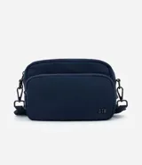Cartera bandolera de tamaño pequeño, confeccionada en poliéster con estructura ligeramente acolchada. Cuenta con un bolsillo delantero con cierre, compartimento principal con cierre doble y correa ajustable.