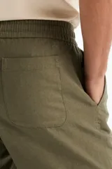 Short de lino color verde militar, de corte recto, con cintura elástica ajustable mediante cordón y bolsillos laterales.