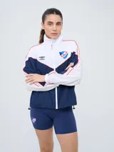 Campera deportiva Umbro del Club Nacional de Football, modelo Sky para mujer. Diseño en tonos azul marino y celeste con detalles en blanco y líneas finas rosadas, cuello alto, cierre frontal y bolsillos.