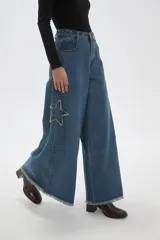 Pantalon de jean negro de corte ancho y tiro alto, con detalle de estrella bordada en la pierna y ruedo deshilachado.