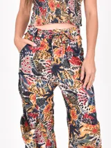 Pantalón cargo de tiro alto con estampado floral y animal print en tonos cálidos y oscuros. Presenta bolsillos cargo voluminosos en los laterales y puños anchos doblados.