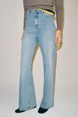 Jeans wide leg de tiro alto y diseño de cinco bolsillos, con efecto lavado, trabillas en la cintura y cierre frontal con cremallera y botón metálico.