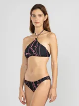 Top de bikini estilo halter color negro con estampado de cadenas y tigres en color rosado. Presenta un charm floral en el cuello. Ofrece protección UV50 y es resistente al cloro, protectores solares y aceites.