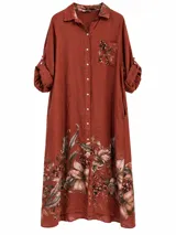 Vestido largo tipo camisero color terracota, con cierre frontal de botones, bolsillos laterales, mangas largas con presilla para arremangar, y un delicado estampado floral en el bolsillo del pecho, el interior del cuello y el ruedo.