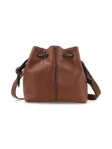 Cartera tipo morral de cuero graneado color marrón terracota, con formato de saco fruncido mediante tiras ajustables oscuras. Presenta una costura decorativa central con tientos a contratono y correa regulable.
