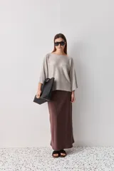 Sweater de punto liviano negro, con escote bote y mangas amplias de largo tres cuartos que aportan una silueta relajada y fluida.